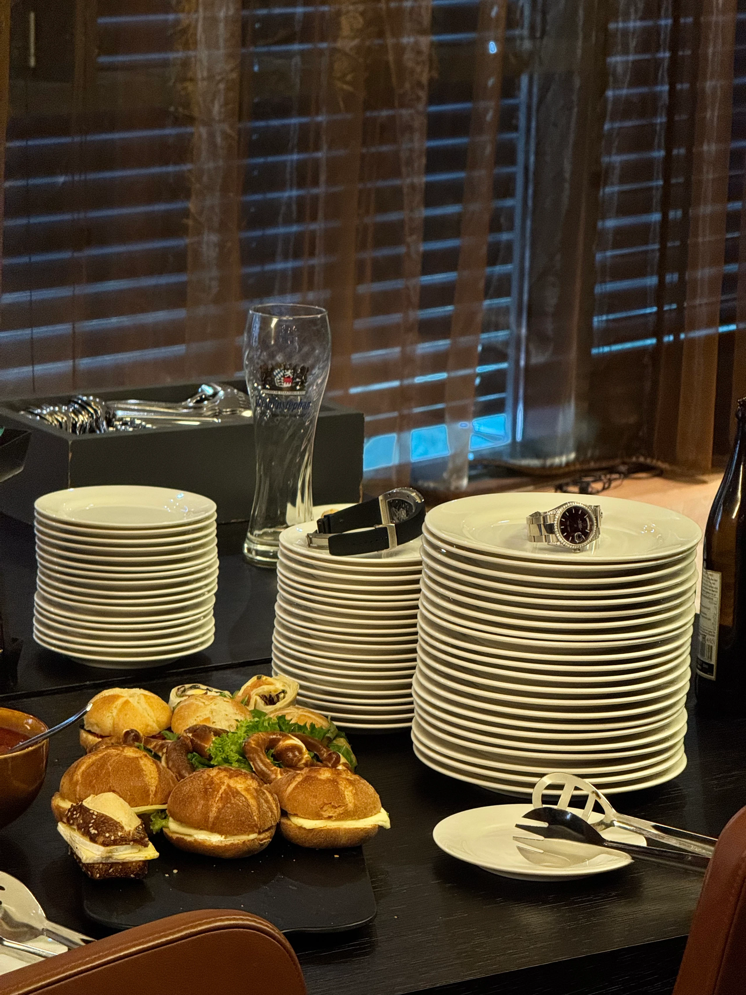 Two watches resting on stacks of plates beside the buffet at the Worldwatch lounge in Munich