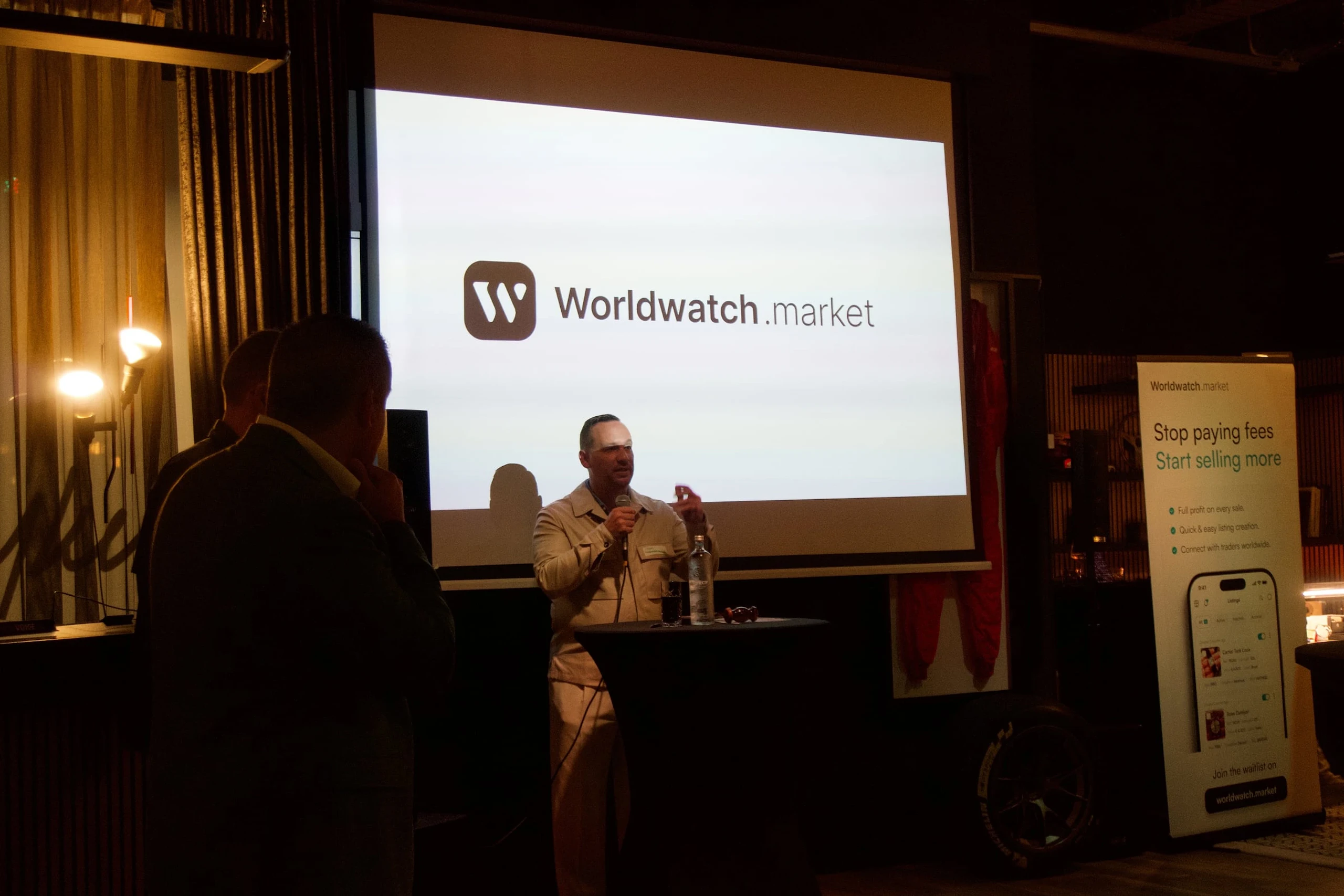 A speaker addressing the room at the Worldwatch launch, the Worldwatch name on the screen behind him